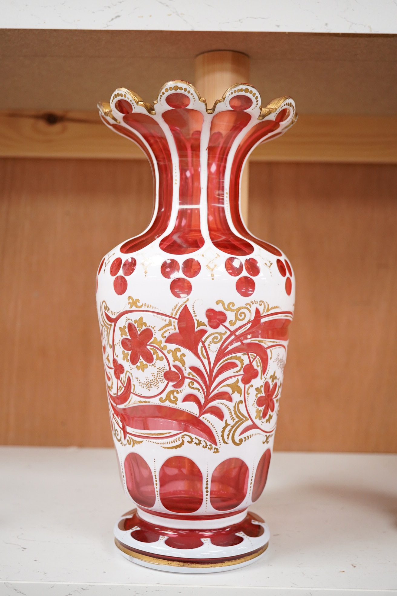 A 19th century Bohemian overlaid and gilt decorated cranberry glass vase, 29cm high. Condition - gilt decoration worn in places